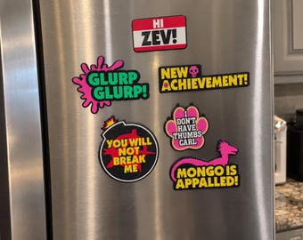 May include: A collection of five colorful magnets featuring text and graphics. The magnets display the phrases HI ZEV!, GLURP GLURP!, NEW ACHIEVEMENT!, I DON'T HAVE THUMBS CARL, YOU WILL NOT BREAK ME, and MONGO IS APPALLED! with various icons.