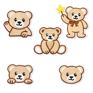 Könnte beinhalten: Fünf gestickte Aufnäher mit hellbraunen Teddybären und dunkelbraunen Umrandungen. Ein Bär winkt, einer hält einen gelben Sternenstab mit brauner Schleife, einer sitzt, einer schaut über eine Kante und einer ist ein einfacher Bärenkopf.