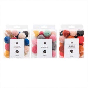 Könnte beinhalten: Drei durchsichtige Kunststoffboxen mit sortierten Garn-Pompons. Jede Box hat ein weißes Etikett mit dem Text Yarn Pompon Set und Made by Me. Die Sets enthalten verschiedene Farben wie Blau, Rosa, Gelb, Rot, Orange, Schwarz und Grau.
