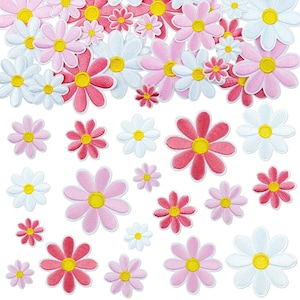 Könnte beinhalten: Eine Sammlung von gestickten Blumenaufnähern in verschiedenen Größen und Schattierungen von Rosa, Weiß und Rot. Jeder Aufnäher hat eine kreisförmige gelbe Mitte, die von abgerundeten Blütenblättern umgeben ist. Die Aufnäher sind verstreut angeordnet.