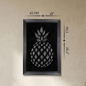May include: Framed black and white artwork depicting a pineapple illustration. The artwork is 45 cm wide and 66.5 cm tall. The pineapple design is set against a black background, creating a striking contrast.