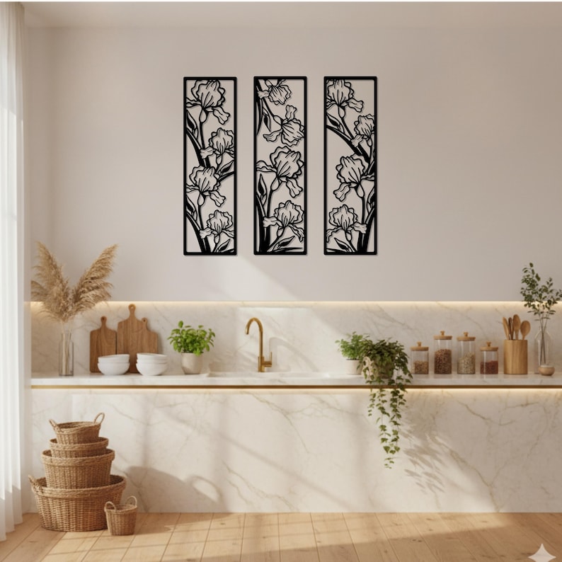 May include: Three black metal wall art panels, each featuring a floral iris design. The panels are rectangular and mounted on a white wall above a kitchen counter. The kitchen has a marble countertop, a gold faucet, and various decorative items.