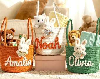 May include: Three woven Easter baskets in orange, white, and green, each with a handle. The orange basket says "Amalia", the white basket says "Noah", and the green basket says "Olivia". Each basket contains toys and a plush bunny.
