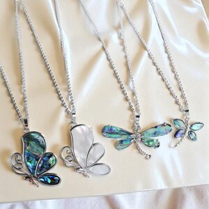Puede incluir: Cuatro collares con colgantes de mariposa y libélula. Los colgantes son plateados y presentan concha de abulón iridiscente y nácar blanco. Los collares tienen delicadas cadenas de plata, perfectas para añadir un toque de elegancia.