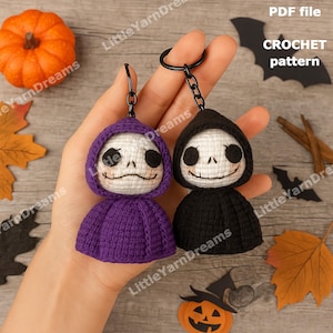 Op de afbeelding: Twee gehaakte sleutelhangers in de vorm van een skelet met een capuchon, één paars en één zwart. Het skelet heeft een lachend gezicht. De afbeelding bevat ook een pompoen, bladeren en de tekst "CROCHET pattern".
