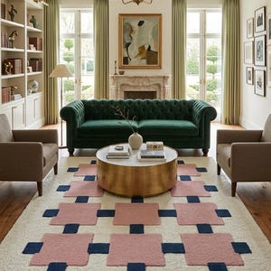 May include: A rectangular area rug featuring a cream-coloured base with a repeating geometric pattern of large, soft pink squares accented by smaller, dark navy blue squares positioned between them, creating a structured grid design on the floor.