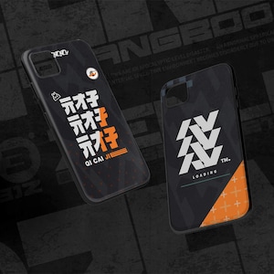 Puede incluir: Dos fundas negras para teléfono con diseños únicos. Una presenta caracteres japoneses y el texto "QI CAI JI" en naranja. La otra tiene un diseño geométrico blanco y la palabra "LOADING".
