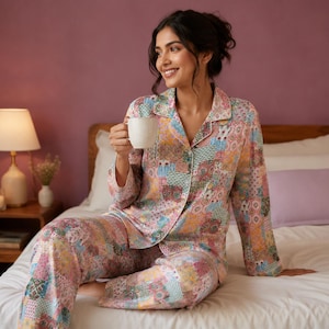 May include: A long-sleeved button-down pajama shirt and matching pajama pants featuring a colorful patchwork pattern with various geometric and floral motifs in shades of pink, yellow, blue, and green, worn with a plain white ceramic mug.