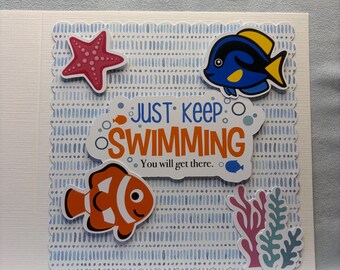 Puede incluir: Una tarjeta blanca con un fondo estampado azul y blanco, con peces de dibujos animados, una estrella de mar y coral. El texto "JUST KEEP SWIMMING" se muestra en naranja y azul, con la frase "You will get there." debajo.