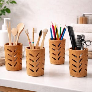 May include: Four bamboo holders with leaf-shaped cutouts. One holds wooden utensils, another toothbrushes, a third colored pencils, and the last a comb and scissors. The holders are on a white surface, ideal for bathroom or desk organization.