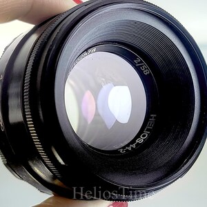 Puede incluir: Un objetivo de c&aacute;mara negro Helios-44-2 con una distancia focal de 58 mm y una apertura de f/2. El objetivo tiene un anillo de enfoque estriado y marcas de apertura. Dise&ntilde;ado para su uso con una c&aacute;mara, tiene un elemento de vidrio transparente.