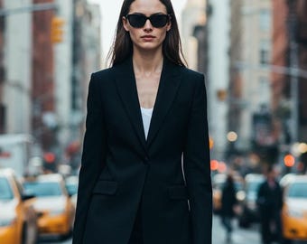 May include: A woman in a black business suit, skirt, and sunglasses walks down a city street. She carries a black handbag and wears black heels. The background features yellow taxis and city buildings.