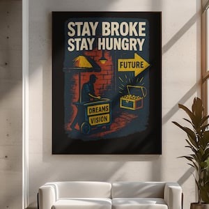 May include: A framed poster with the text "STAY BROKE STAY HUNGRY" in white and yellow. The artwork depicts a street vendor cart with "DREAMS VISION" on it, a treasure chest, and a yellow arrow pointing to "FUTURE". The color palette includes blue, red, and yellow.