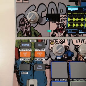 May include: A music production sampler featuring a custom comic book graphic skin. The interface includes grey control knobs, orange and grey buttons labelled Sample, Seq, Pad Fx, and Knob Fx, and a digital screen displaying audio waveforms.