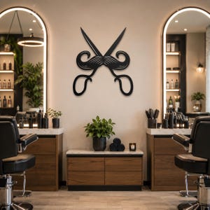 Peut inclure: Une enseigne murale en métal noir représentant un graphisme stylisé de ciseaux de coiffeur croisés intégrés à une grande moustache détaillée. La silhouette est entièrement noire avec des découpes formant la texture des poils.