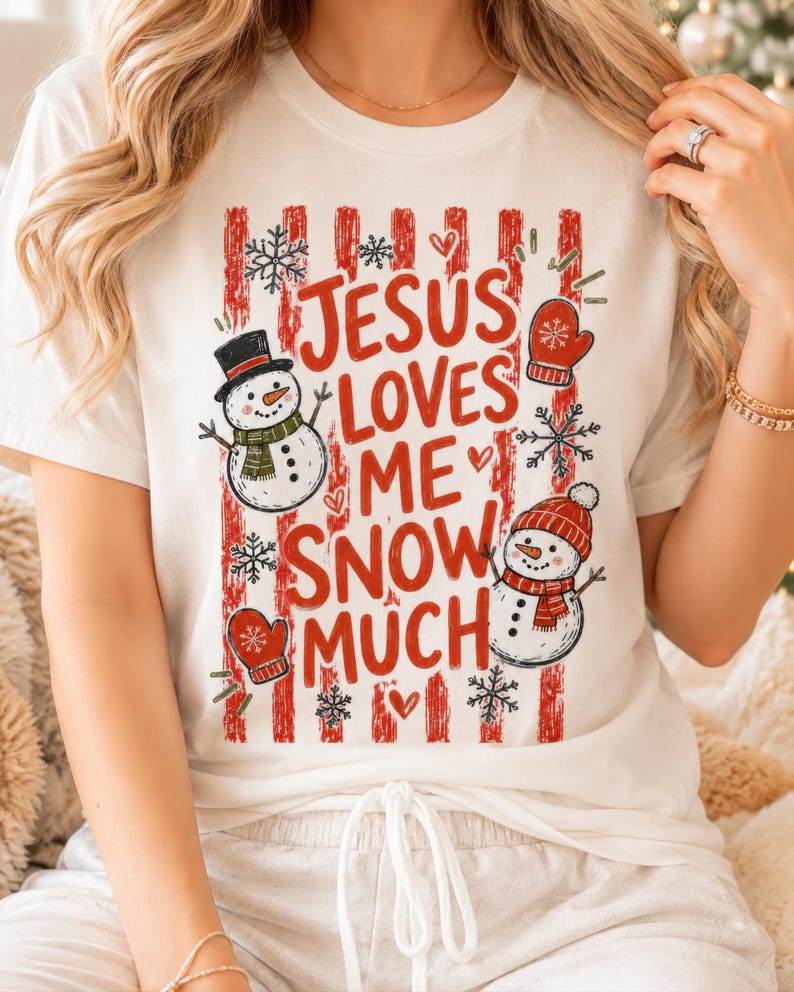 May include: A white short-sleeved t-shirt featuring a red vertical striped background with the text "JESUS LOVES ME SNOW MUCH" in red letters. The design includes two snowmen, red mittens, and black and white snowflakes scattered throughout.