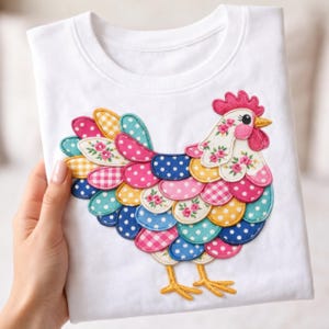 以下が含まれることがあります： 白いクルーネックTシャツ。カラフルな鶏のアップリケが特徴です。鶏のデザインは、ピンク、青、黄色、白の色合いのドット、ギンガム、フローラルプリントなどのさまざまなパターンを取り入れています。鶏は黄色の足とピンクの鶏冠を持っています。