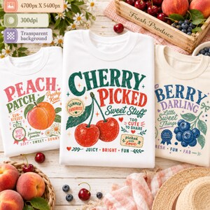 May include: Three white t-shirts featuring colorful graphic prints. The left shirt displays a peach with the text Peach Patch. The center shirt shows two cherries with the text Cherry Picked Sweet Stuff. The right shirt features blueberries with the text Berry Darling.