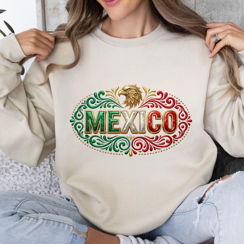 May include: A beige crewneck sweatshirt featuring a central graphic of a golden eagle head above the word MEXICO in block letters. The text and surrounding ornate filigree patterns are colored in shades of green, white, and red.