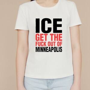May include: White t-shirt featuring the text "ICE GET THE FUCK OUT OF MINNEAPOLIS" in black and red block letters. The shirt has a crew neck.