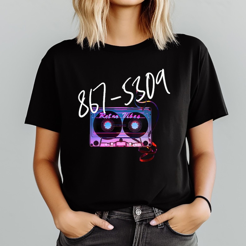 May include: Black t-shirt featuring a retro cassette tape design with the text "Retro Vibes" and the phone number 867-5309 in white script. The cassette tape design has purple, blue, and pink hues.