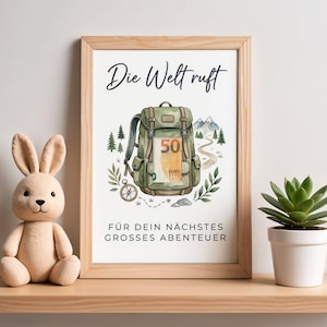 Może przedstawiać: Oprawiony wydruk z tekstem "Die Welt ruft" i "Für dein nächstes großes Abenteuer". Grafika przedstawia zielony plecak z banknotem 50 euro, kompasem, górami i drzewami. Rama jest jasnobrązowa.
