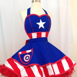 Inspired by Captain America,  a red, white, and blue apron with a heart-shaped top and a star in the center. The apron has a pocket on the front with a bullseye design. The lower skirt is a wide red and white stripe. The apron is made of 100% cotton fabric.