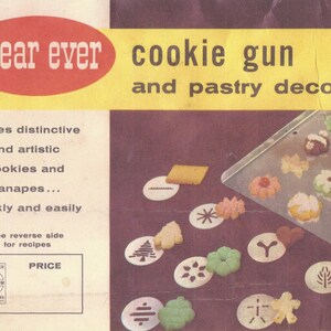May include: A vintage Wear Ever cookie gun and pastry decorating set with a red and yellow label. The set includes a variety of metal cookie cutters and a dial for adjusting the size of the cookies. The image also shows a baking sheet with cookies and pastry decorations.