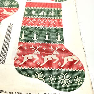 以下が含まれることがあります： 赤、緑、白のクリスマスストッキングのパターン。デザインはトナカイ、木、幾何学模様が特徴です。ストッキングは布製で、ヴィンテージの手作り感があります。側面のテキストは「P screen print」と書かれています。