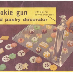 May include: A silver cookie gun and pastry decorator with a dial for cookie thickness. The gun is on a baking sheet with various cookie shapes and sizes. The cookie shapes are on a purple surface.