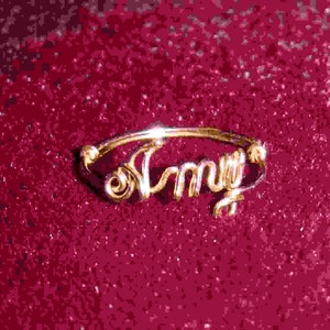 May include: A gold-colored ring with the word "Amy" spelled out in cursive.