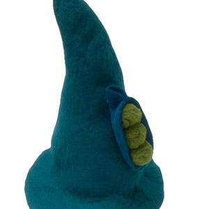 May include: A teal felted hat with a pointed crown and a wide brim. The hat features a lime green pom-pom at the very tip and a side pocket detail in a darker blue shade, which contains three small, round, lime green felted spheres inside.