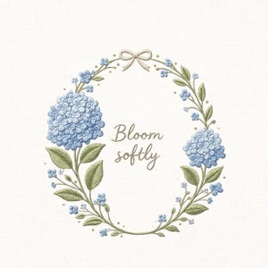 Puede incluir: Corona floral bordada con hortensias azules, hojas verdes y pequeñas flores azules. Un lazo beige claro está en la parte superior. Las palabras "Bloom softly" están escritas en una fuente de guion dentro de la corona.
