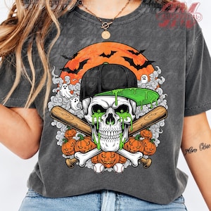 May include: A charcoal gray t-shirt featuring a graphic of a skull wearing a black baseball cap with a green brim. The skull has green slime dripping from its eyes, positioned over crossed baseball bats, pumpkins, and two baseballs.