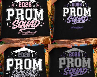 May include: Black square pillow with the text "2026 PROM SQUAD" in white and pink, with a graduation cap graphic. The phrase "#Proud Moment" is below the text. The pillow is held up by hands.
