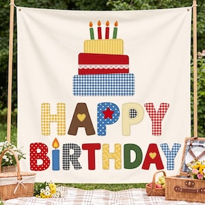 Könnte beinhalten: Ein cremefarbenes Stoffbanner mit einer dreistöckigen Geburtstagstortengrafik und brennenden Kerzen. Unter der Torte steht der Text HAPPY BIRTHDAY in großen, mehrfarbigen Buchstaben mit verschiedenen Mustern wie Vichy-Karo, Punkten und Unifarben.