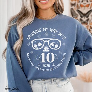 May include: Blue jean sweatshirt with a white graphic that reads "Cruising My Way Into 40 Making Memories Together 2026." The graphic includes sunglasses with palm trees, a ship, and nautical icons.