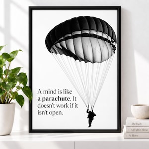 May include: A black and white framed wall art print featuring a large parachute canopy and a silhouette of a person descending. The text reads: A mind is like a parachute. It doesn't work if it isn't open. The design is set against a white background.