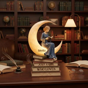 Può includere: Lampada decorativa raffigurante una donna che legge su una luna crescente, sopra una pila di libri. I libri recitano "JUST A GIRL WHO LOVES BOOKS". La lampada ha un bagliore caldo, con il nome "Stella" sulla luna. La donna indossa un abito blu.