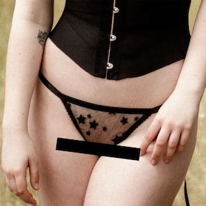 May include: Black lace underwear with a star pattern. The underwear is a thong style with a low rise.