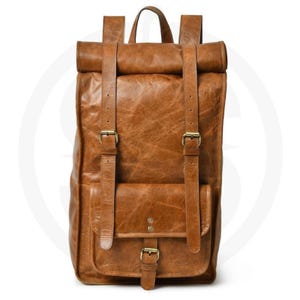 Könnte beinhalten: Ein brauner Lederrucksack mit Rollverschluss und verstellbaren Schultergurten. Der Rucksack hat eine Vordertasche mit Schnallenverschluss und einen oberen Griff. Das Leder hat einen Used-Look mit sichtbarer Maserung und Textur.