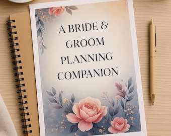 May include: A spiral-bound notebook and a pen rest on a wooden surface next to a cup of coffee. The notebook features the text "A Bride & Groom Planning Companion" with a floral design in pink and blue.