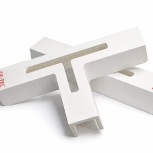 May include: Two white, T-shaped objects are stacked and angled against each other. Each has a rectangular body with a cutout and the red text "GE-TEC" printed on the side. The objects are on a white background.