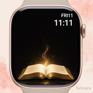 May include: A rose gold smartwatch with a digital display showing the time 11:11 and the date FRI 11. The screen features a graphic of an open book with glowing golden light emanating from its pages against a dark, black background.