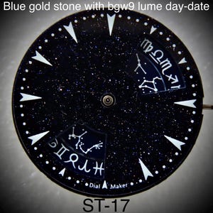 Puede incluir: Una esfera de reloj con un fondo azul oscuro salpicado de motas doradas. Marcadores triangulares blancos y pequeños puntos rodean la esfera. Dos secciones muestran constelaciones del zodíaco. El texto "Dial Maker" y "ST-17" son visibles.