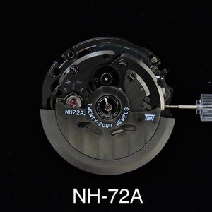 May include: A close-up of a watch movement, featuring intricate gears and components. The movement is primarily black with silver accents, and the text "NH72A" is visible. The words "Twenty-Four Jewels" are also printed on the movement.