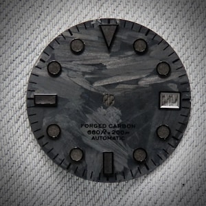 May include: A watch face with a forged carbon design. The face is dark gray with a textured pattern and features circular and rectangular markers. The text "FORGED CARBON 660ft - 200m AUTOMATIC" is printed on the face.
