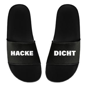 May include: A pair of black slide sandals. Each sandal has a wide strap with the words "HACKE" and "DICHT" printed in white. The sandals are designed for casual wear.