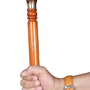Könnte beinhalten: Ein Gehstock mit einem polierten Holzschaft und einem detaillierten, dunkelbraunen Metallgriff in Form eines Kaninchenkopfes. Der Griff ist durch eine silberfarbene Metallmanschette mit dem Schaft verbunden, was einen Kontrast zur Holzmaserung bildet.