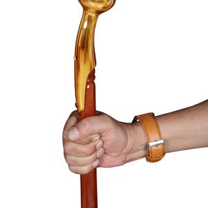 Puede incluir: Un bastón con un mango de metal dorado pulido con una parte superior redondeada y bulbosa. El eje está hecho de madera lisa de color marrón rojizo con un acabado brillante e incluye un anillo decorativo de metal color latón bajo el mango.